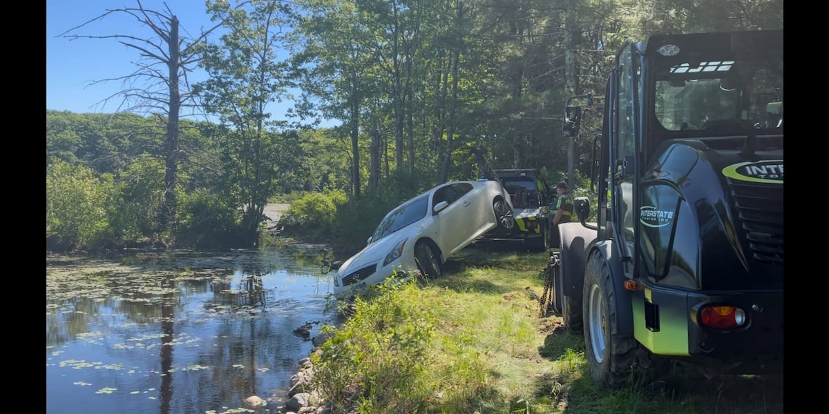 First responders pull car partially submerged in pond