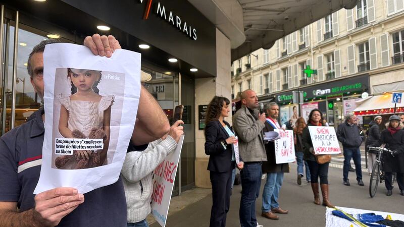 A protester holds a picture of a childlike sex doll outside BHV Marais department store in...
